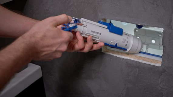 Een man installeert een Geberit spoelventiel in een inbouwreservoir (© Ben Huggler) Een man installeert een Geberit spoelventiel in een inbouwreservoir (© Ben Huggler)